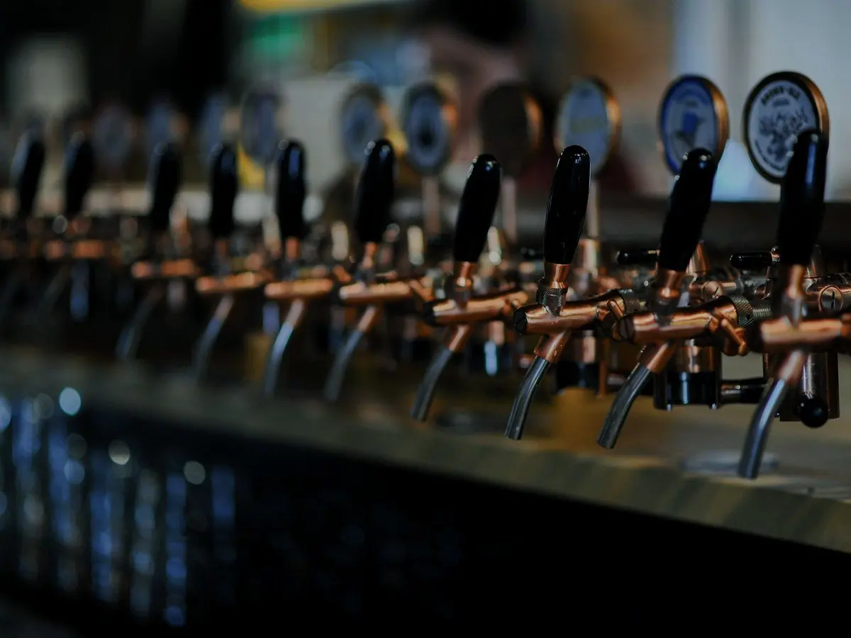 A row of copper beer taps along a bar